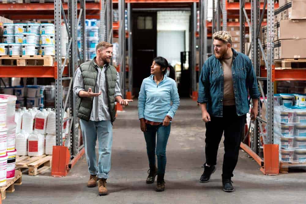 Three workers walking through a warehouse aisle depicting industry-specific positive duty challenges in the workplace.